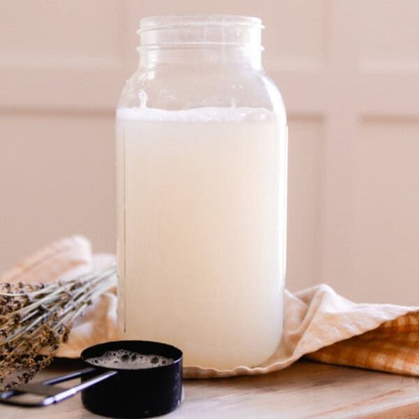 A mason jar with homemade laundry detergent next to dried lavender and a measuring cup.