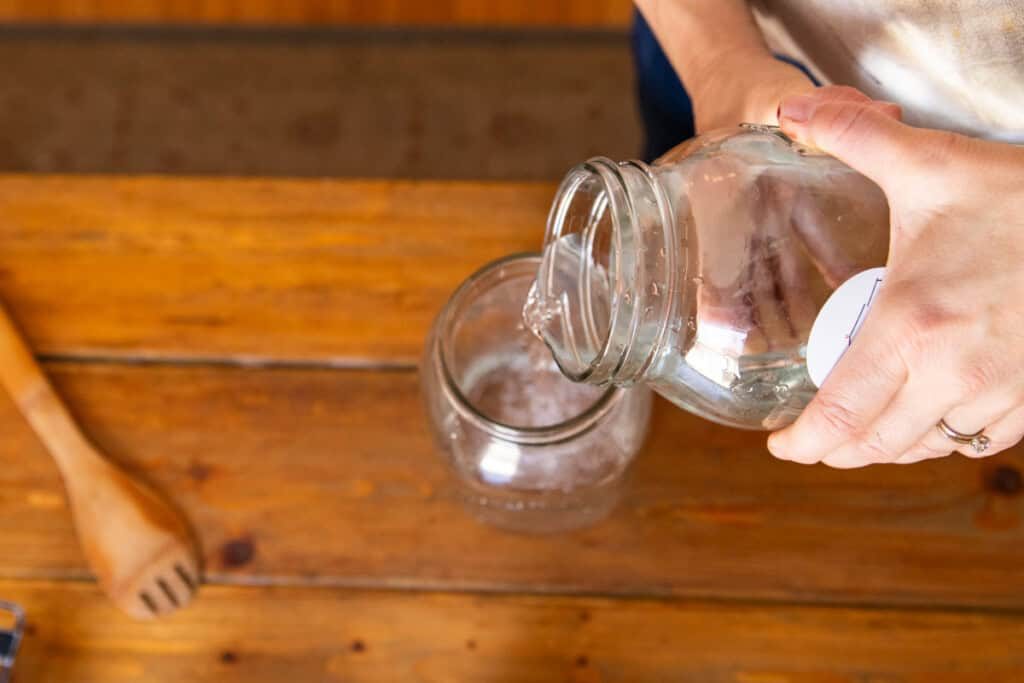 Pouring water into a large glass jar.
