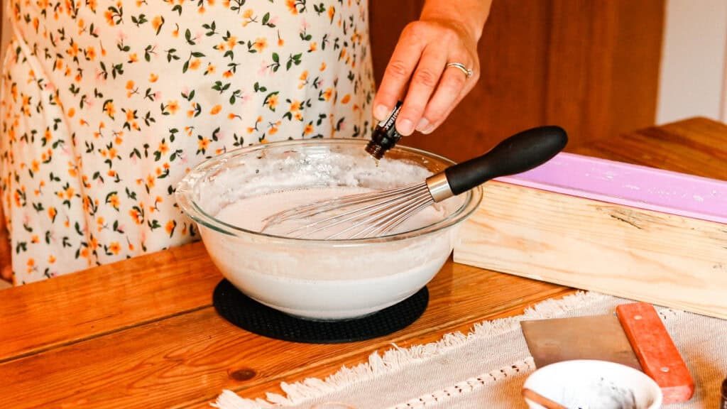 Adding drops of essential oils into the melted soap base mixture to make soap on a rope.