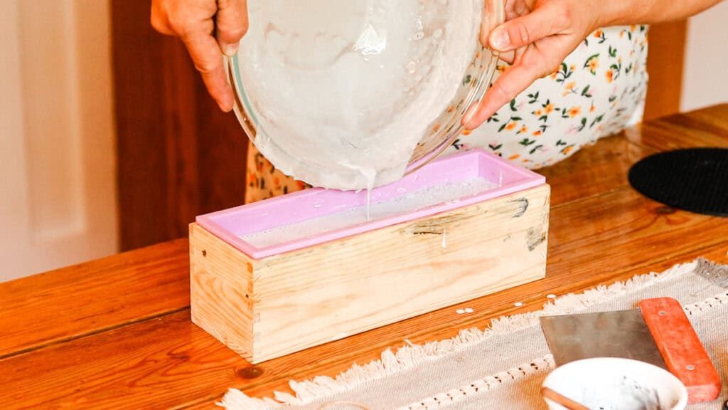 Pouring the melted soap mixture into a silicone loaf mold.