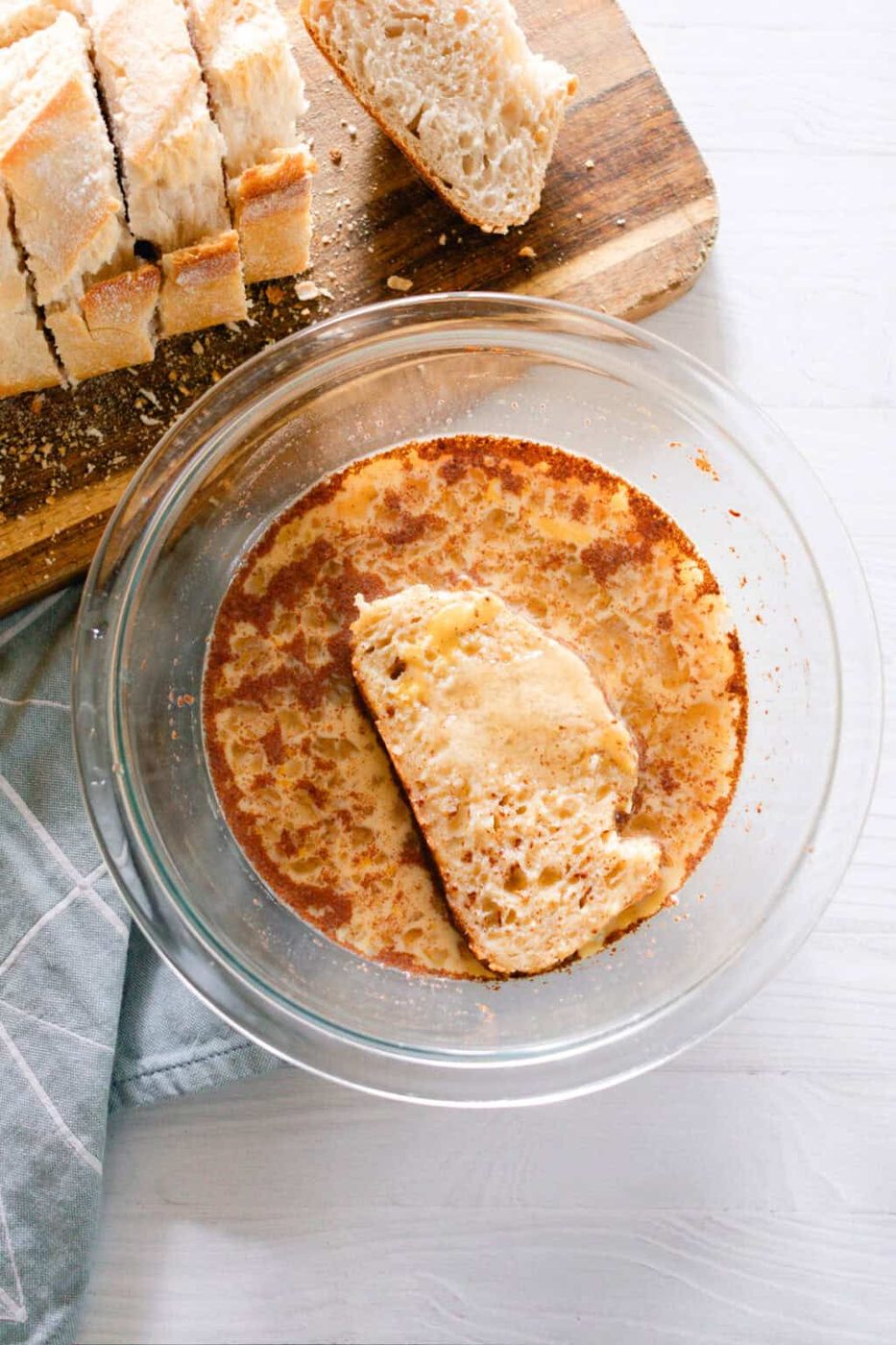 Dipping a slice of bread in the egg mixture.