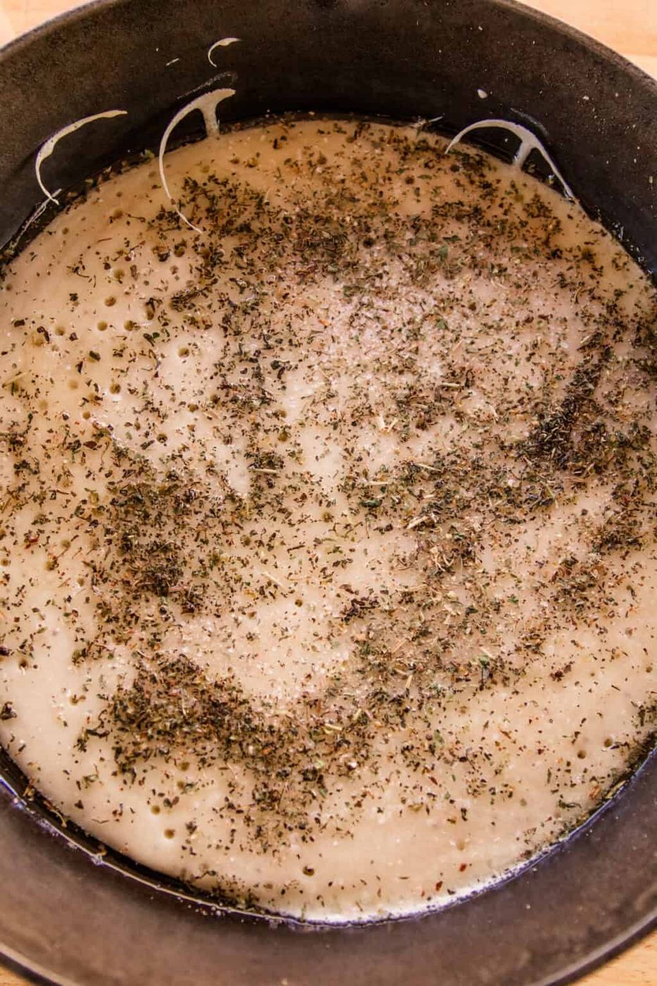 Sourdough pizza crust with herbs sprinkled on it.