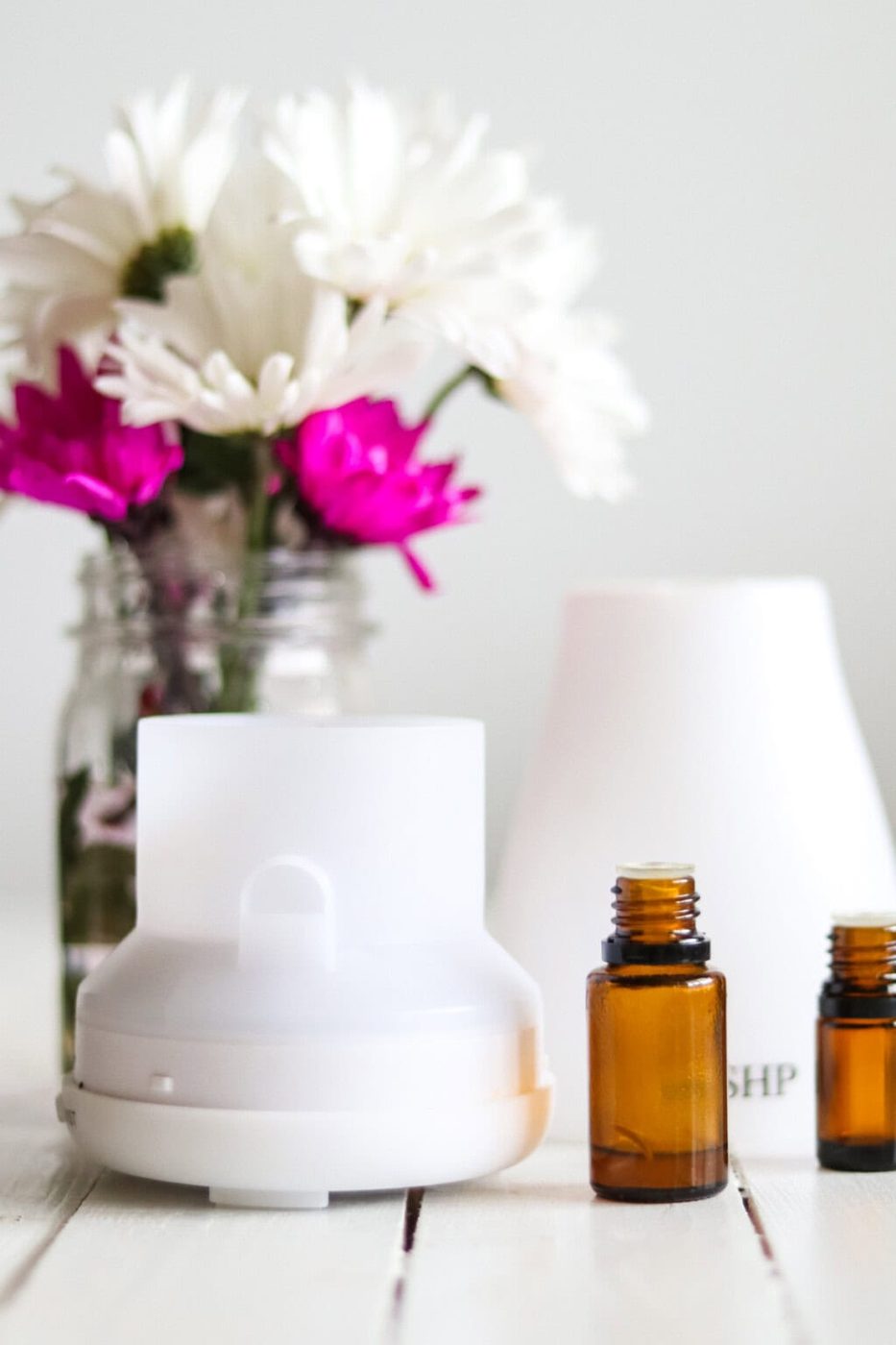 A diffuser with bottles of essential oils and fresh flowers.