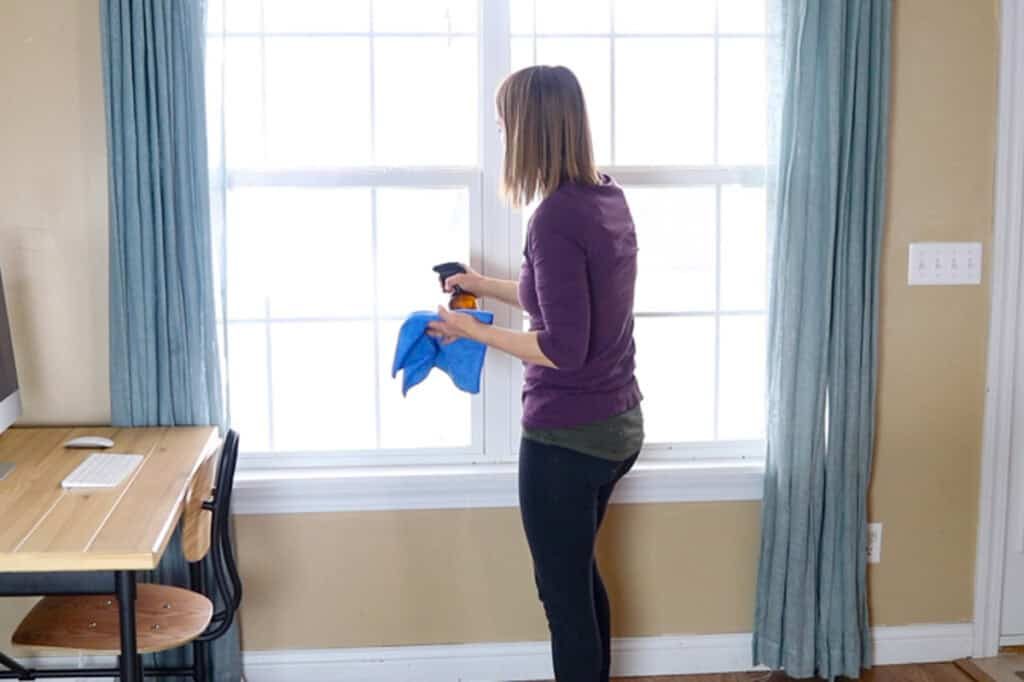 Cleaning large windows with a spray bottle and rag.