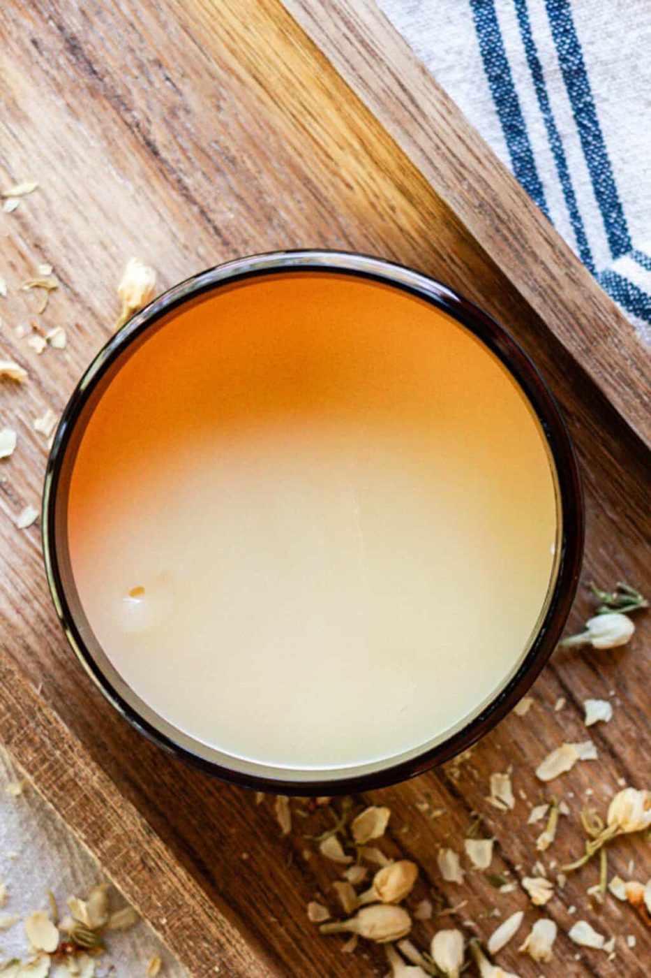 Homemade tallow balm in an amber jar on a wooden board.