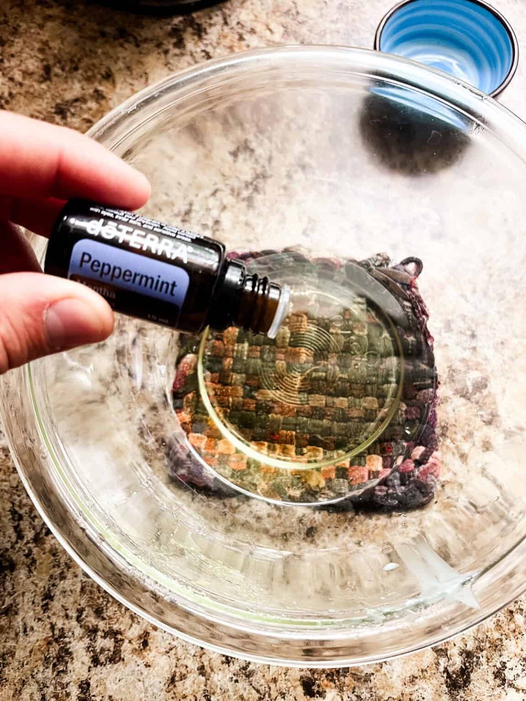 Dropping essential oils into a melted bowl of tallow lip balm ingredients.