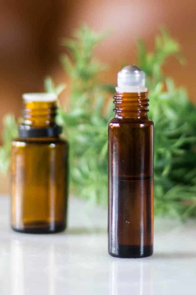 tea tree essential oil with a 10ml glass bottle on marble with green sprigs in background