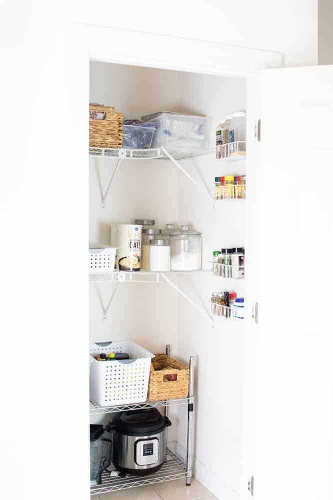 Organized pantry with white walls and white shelves.
