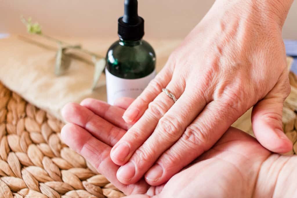 A bottle of vitamin C serum being applied to hands.