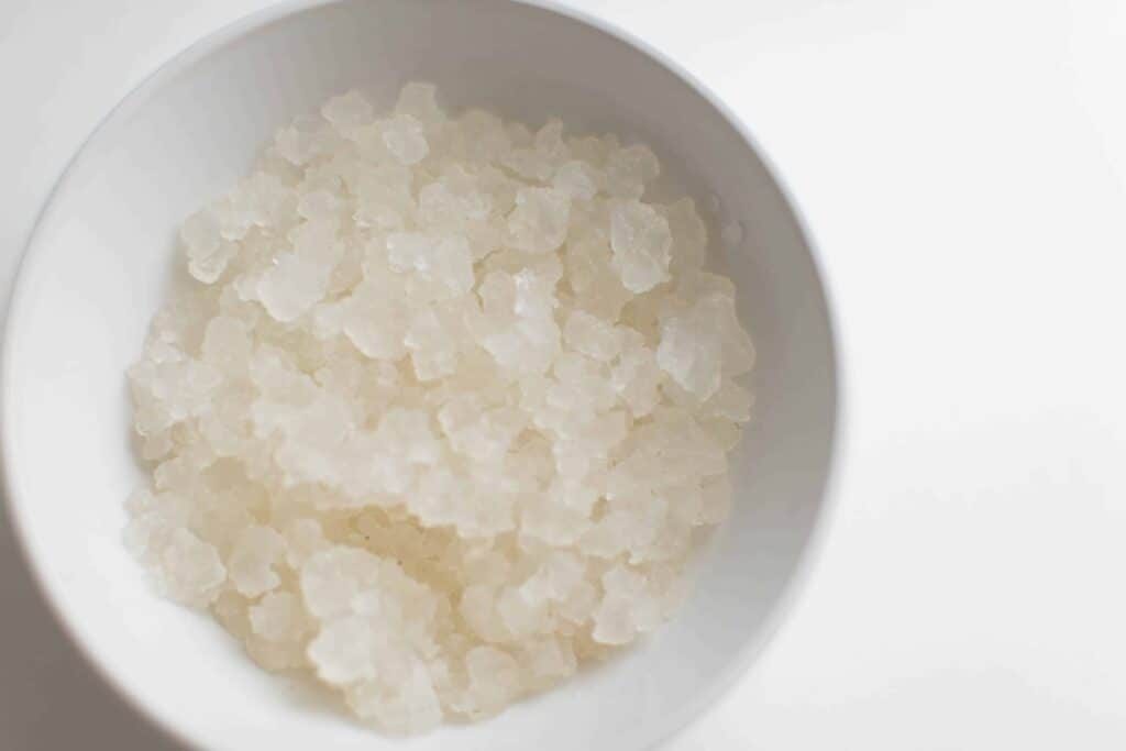 Water kefir grains in white bowl on white table.