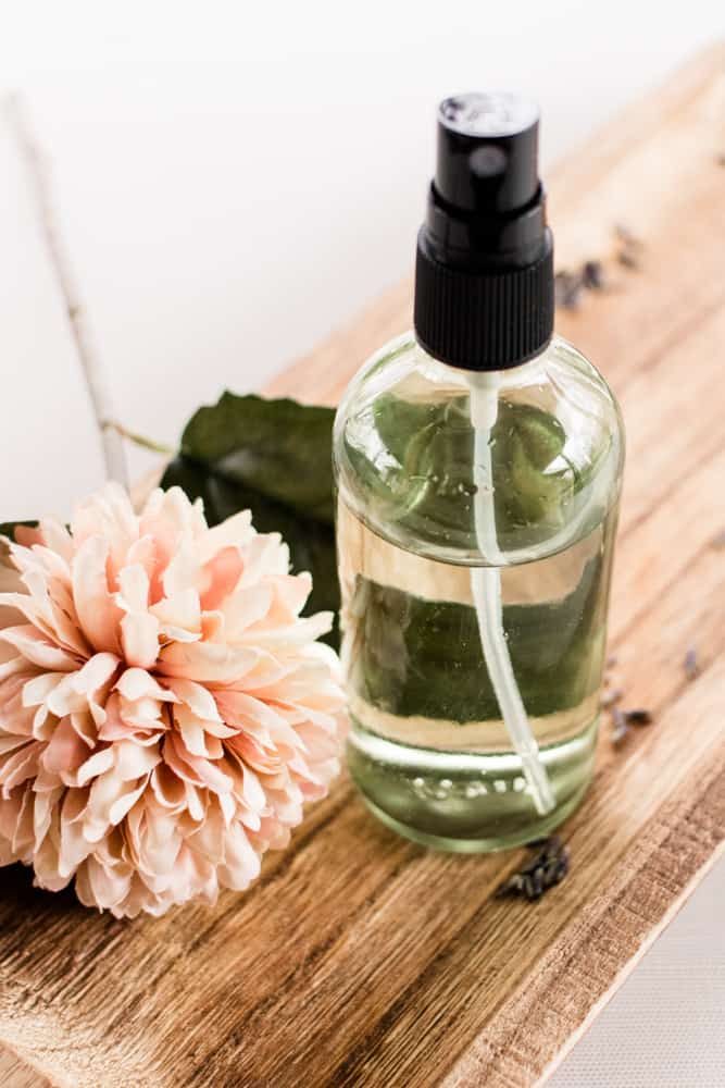 Body mist with flowers on a wooden board.