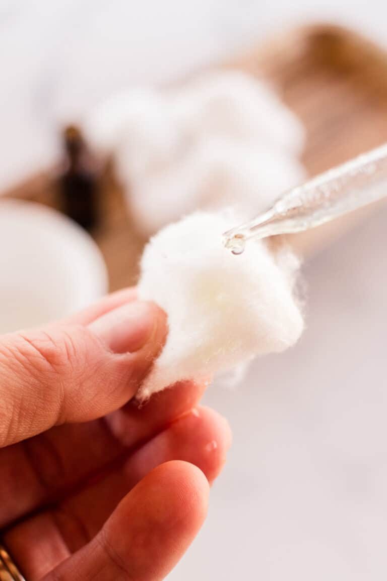 Applying tea tree oil to a cotton ball.