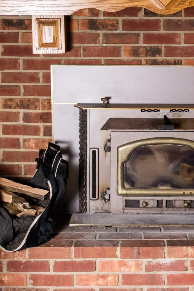 Wood burning stove insert with brick fireplace.