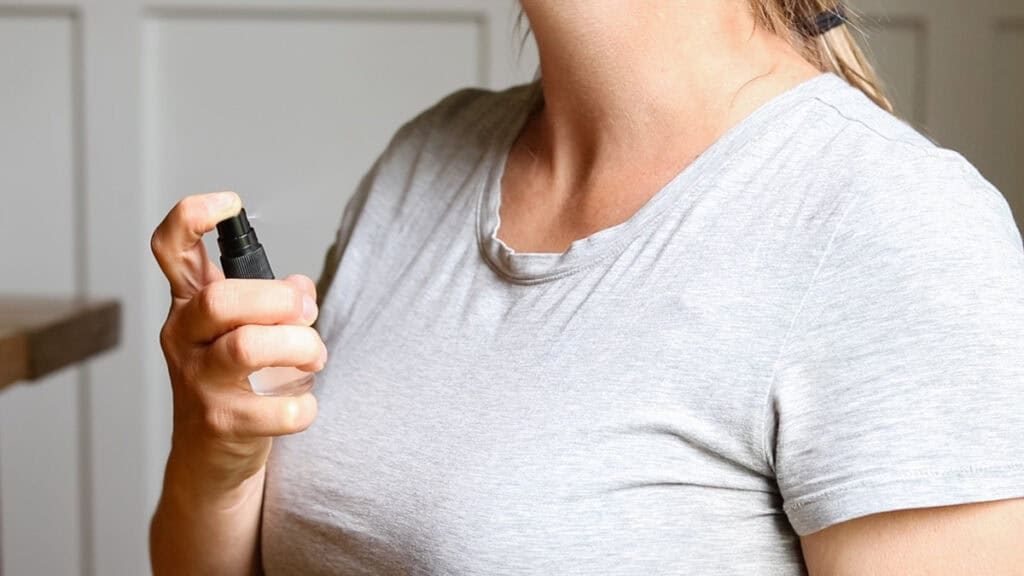 Applying homemade spray perfume by misting it onto the neck.