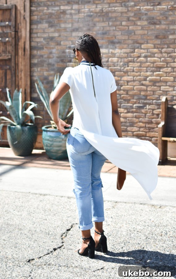 Side profile of the outfit, highlighting the flow of the high-low hem and the texture of the clutch.