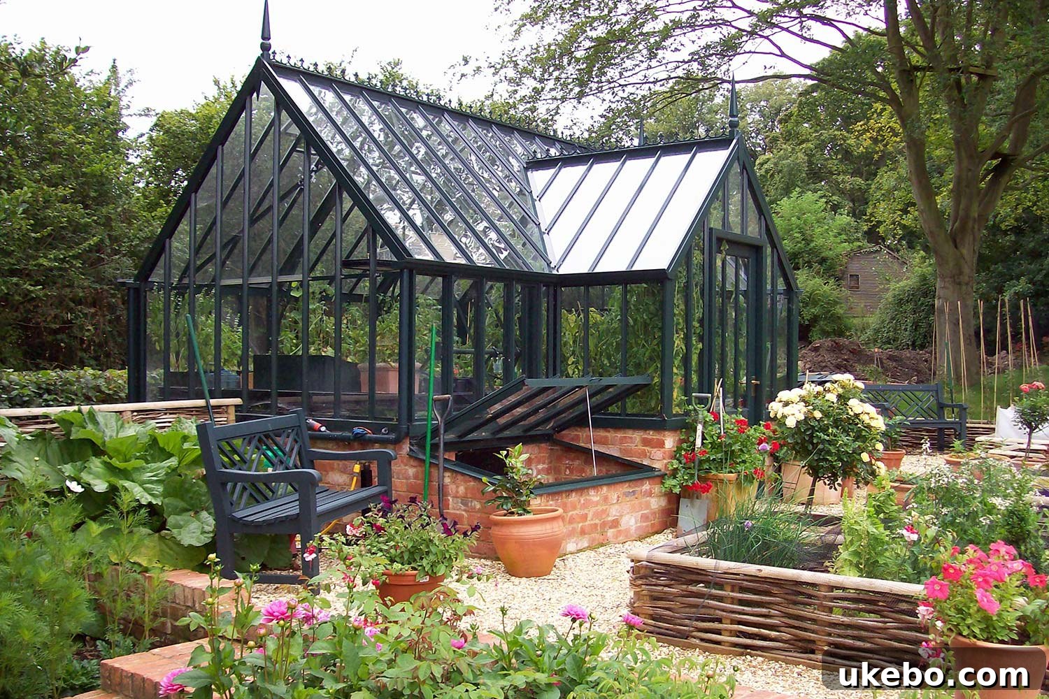 Large black greenhouse integrated into a landscaped garden