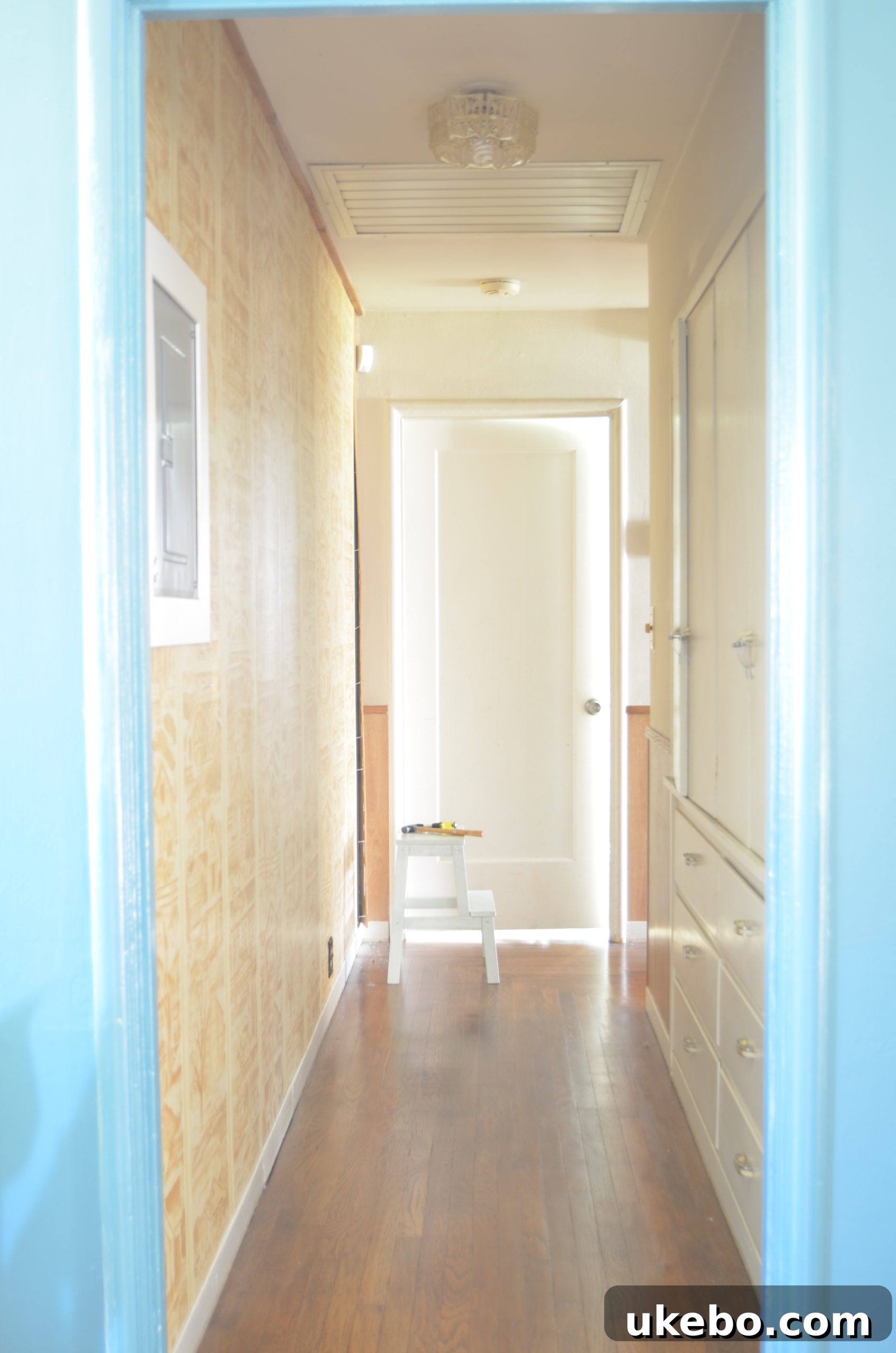 Hallway before makeover: Dark, mismatched wood paneling and wainscoting, poor lighting