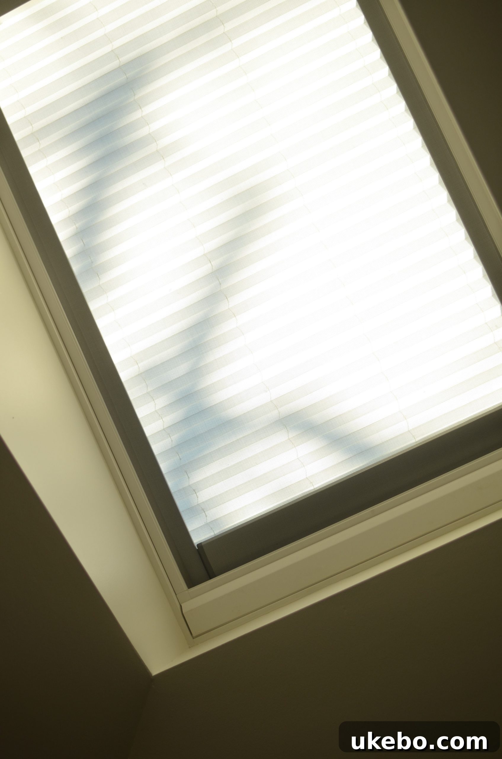 Velux skylight with its integrated cream-colored blind partially closed, blending seamlessly with the ceiling.