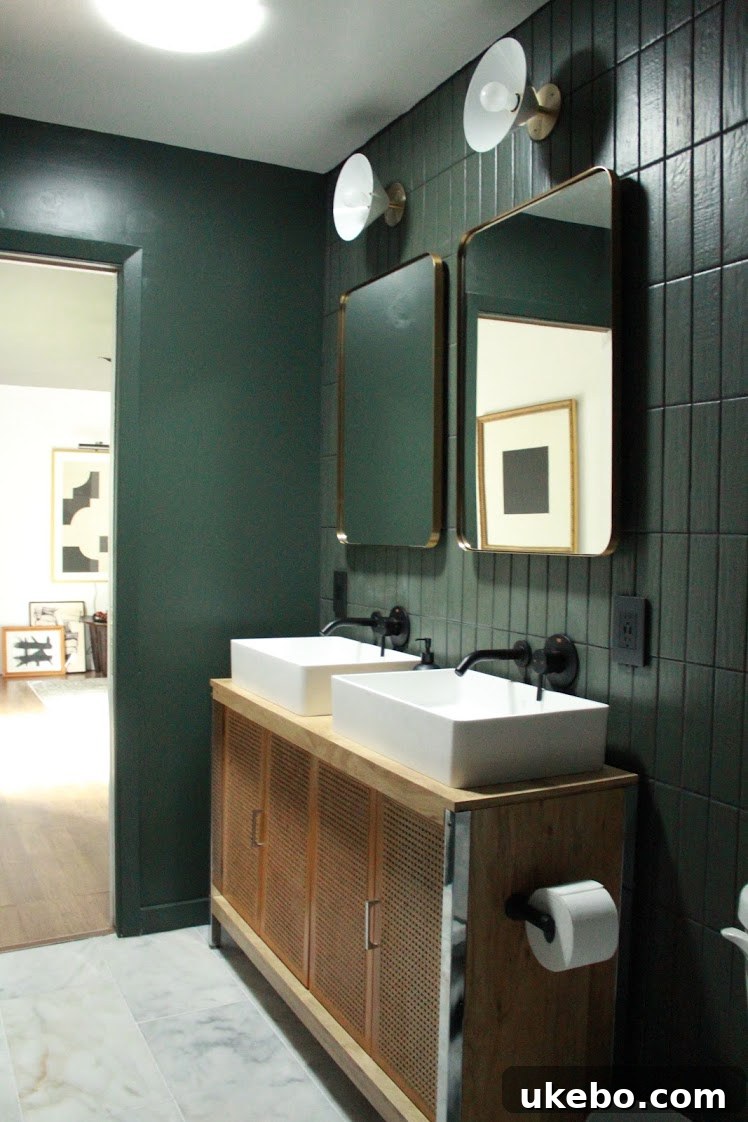 Army green subway tiles on the walls and oversized polished marble flooring in the renovated bathroom