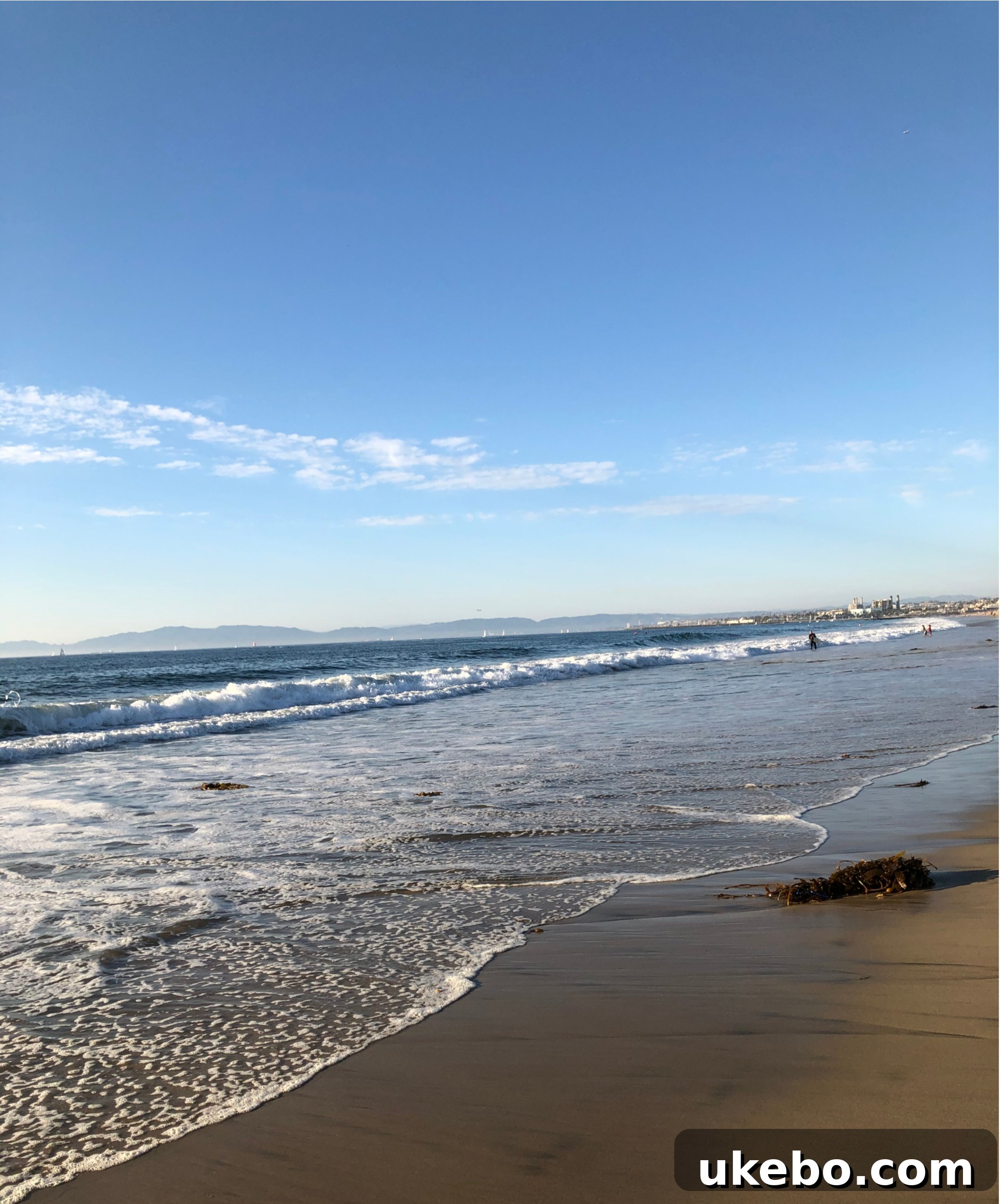 Panoramic view of the serene Torrance Beach with calm waves and few people.
