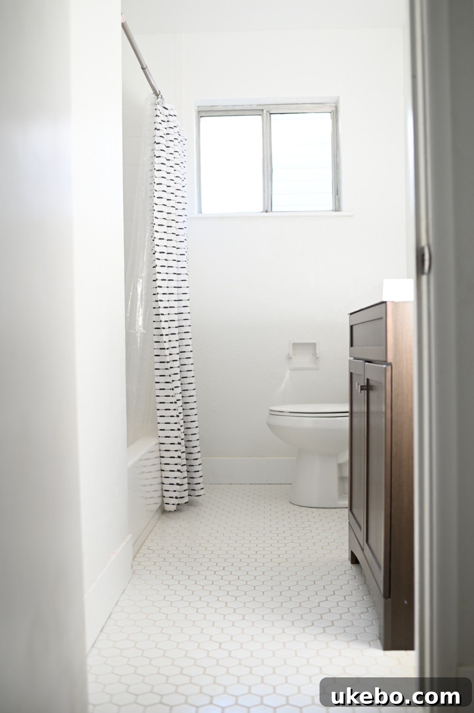 Before photos of a dated bathroom with white tile floors and a white vanity.