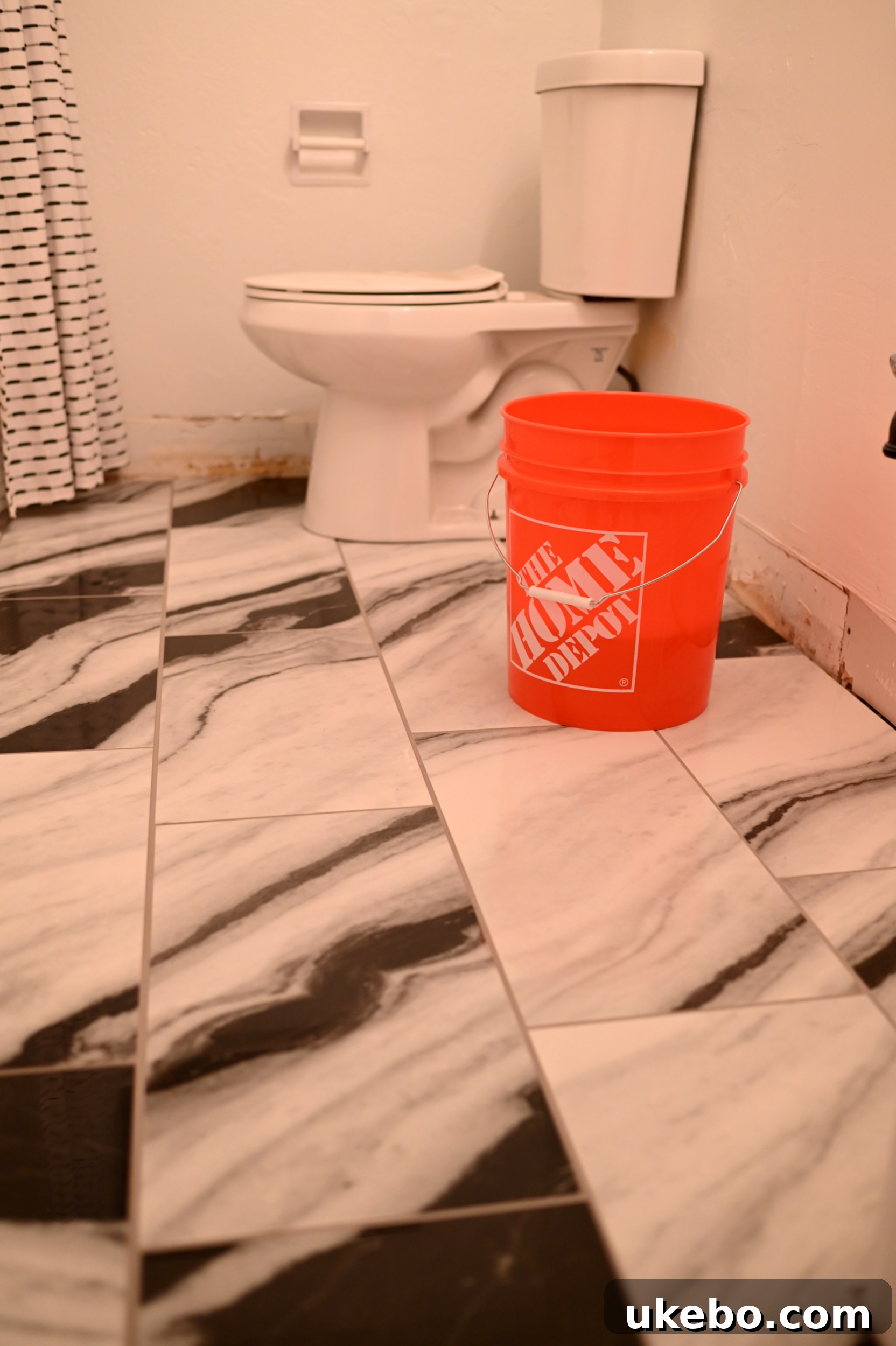 A wider shot of the bathroom floor after grout application, showcasing the clean lines of the Panda Marble QuicTile.