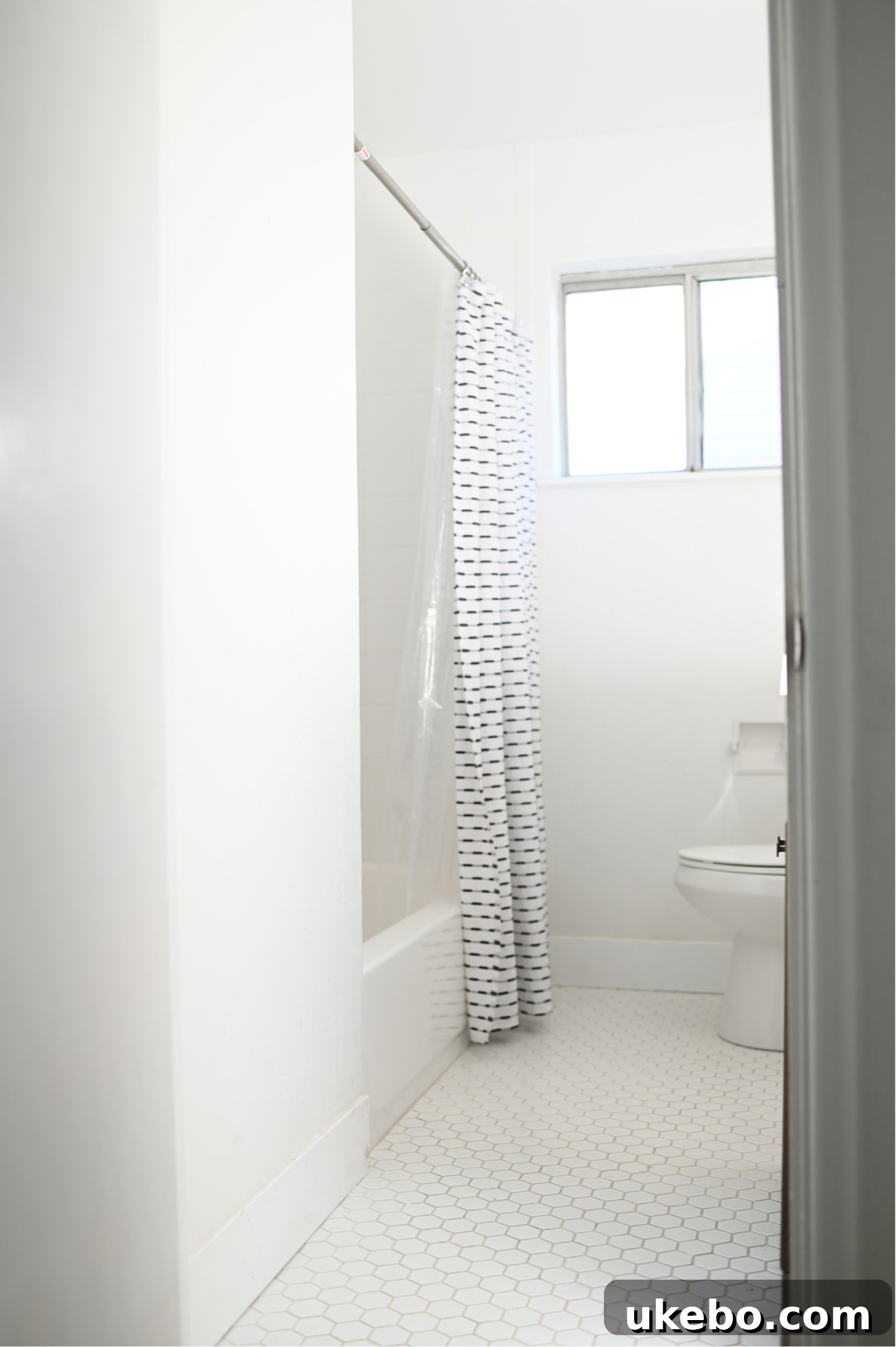 A third before photo of the bathroom, highlighting the tired white tile floors and a basic toilet.