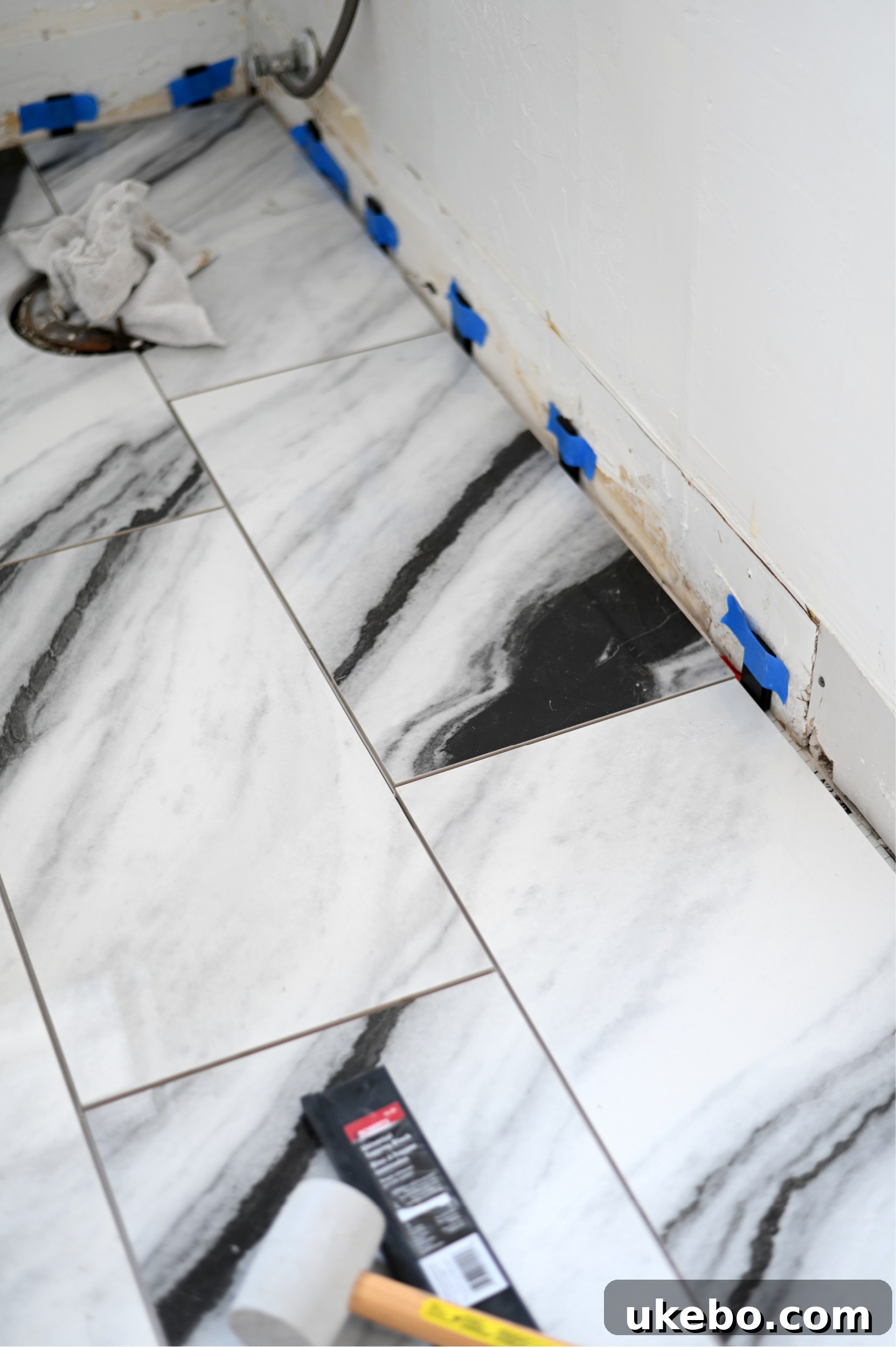 A view of the bathroom floor with the new QuicTile partially installed, showing the elegant Panda Marble pattern.