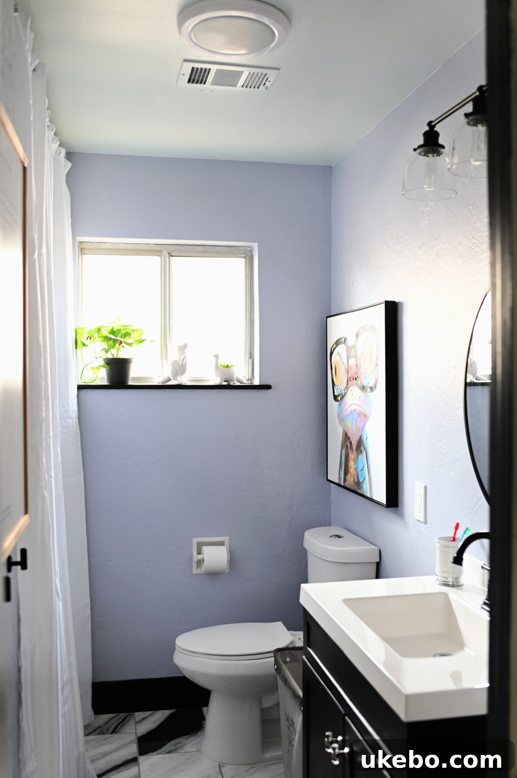 Interior view of a light blue bathroom featuring a modern black vanity and faucet, highlighting Sherwin-Williams paint.