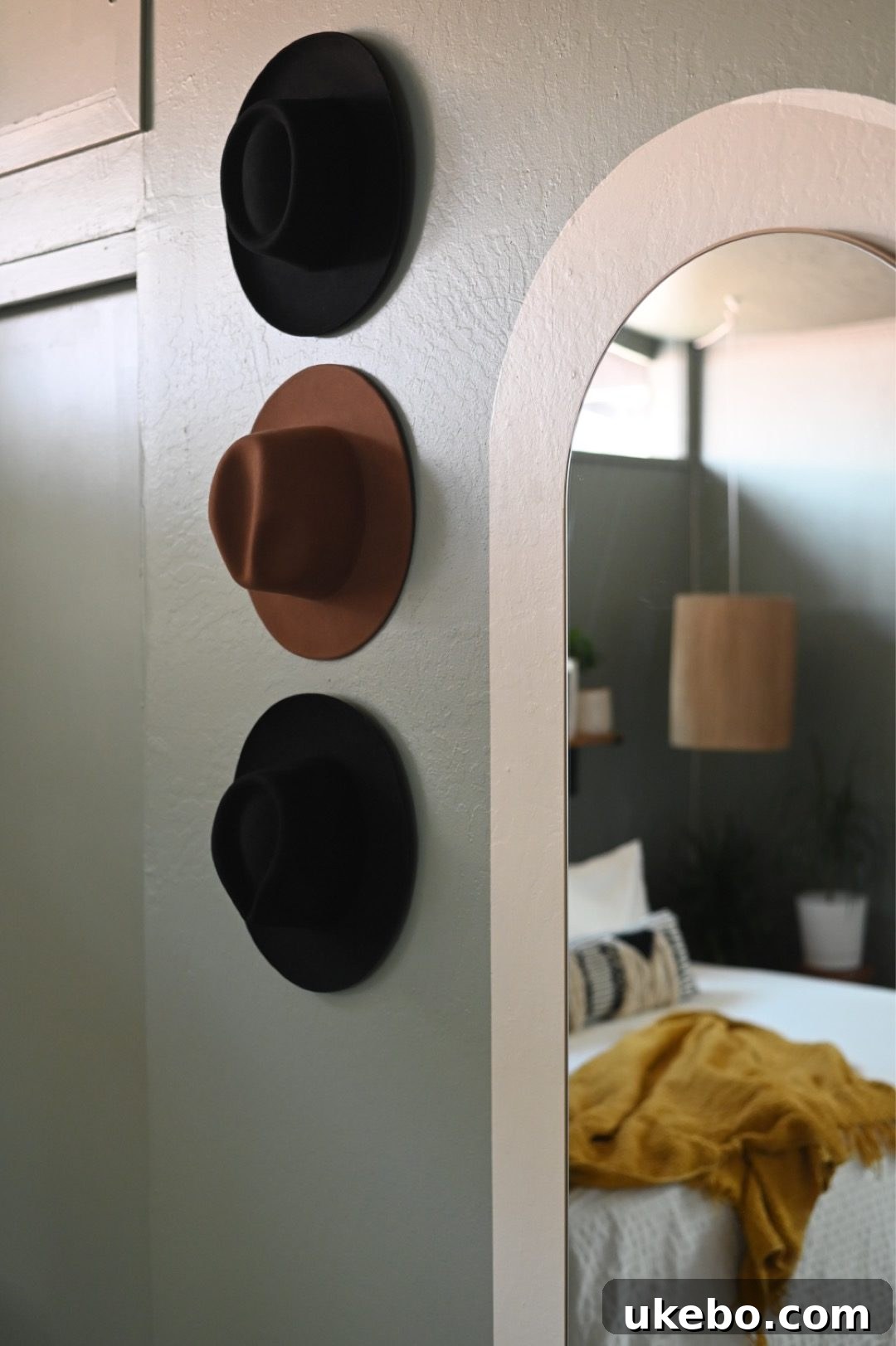 A view of the minimalistic bedside shelf with a small plant and decorative item, against the calming Evergreen Fog wall.