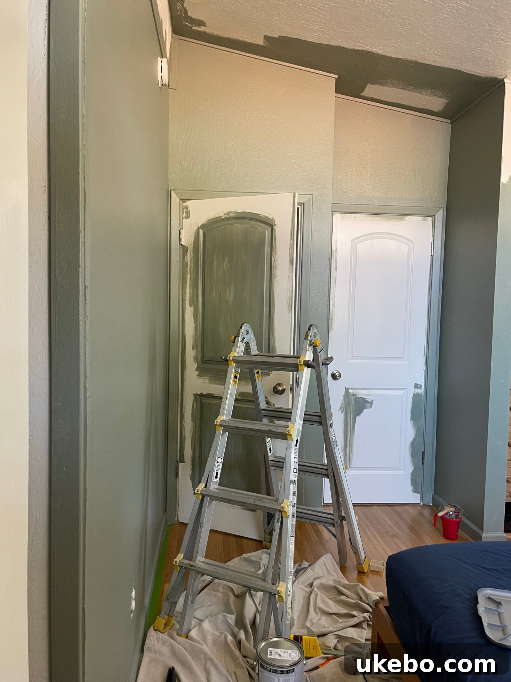A close-up before photo of a white bedroom wall, showing the texture and the readiness for a fresh coat of Evergreen Fog paint.