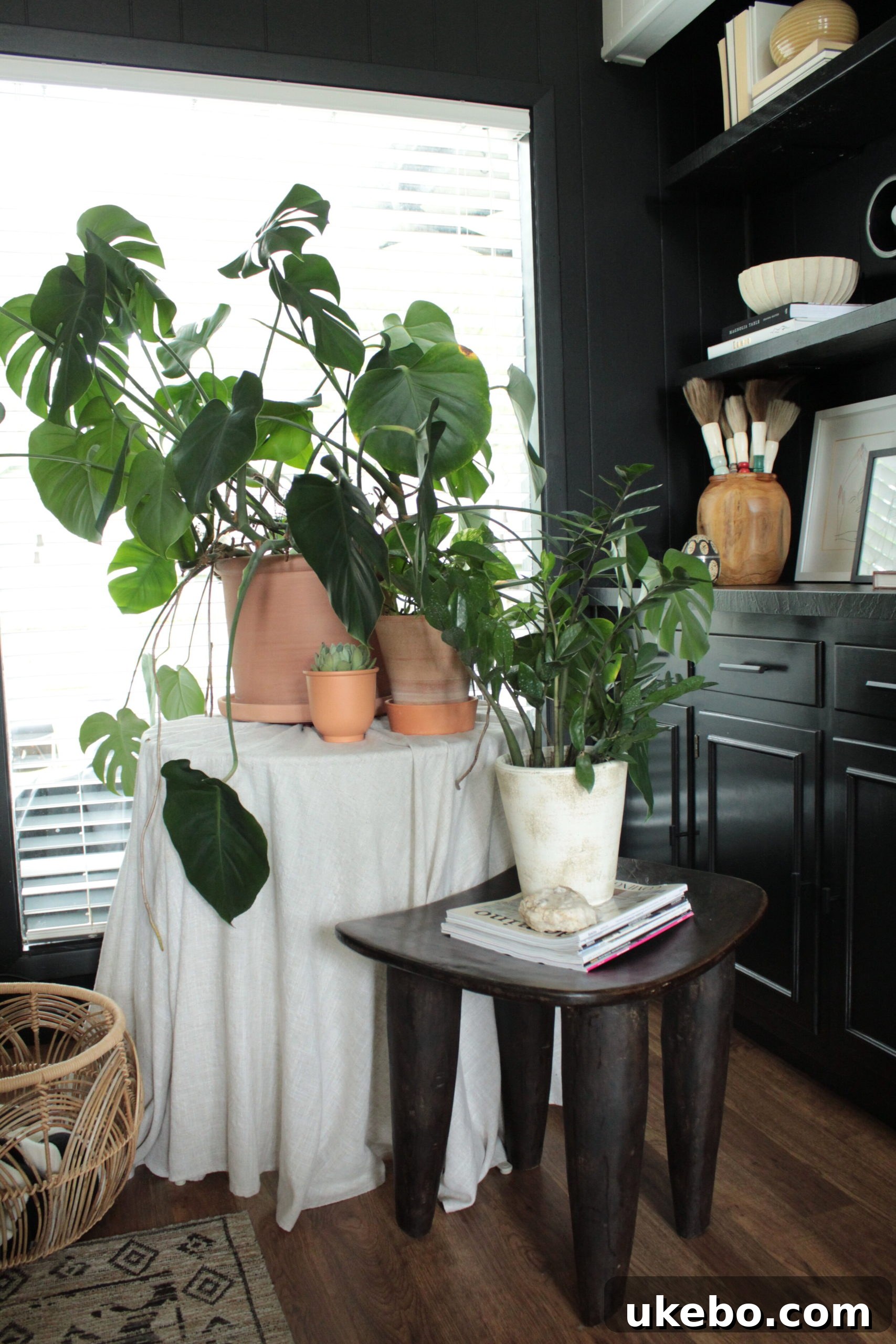 A Senufo stool used as a stylish side table next to an armchair, showcasing its versatility.
