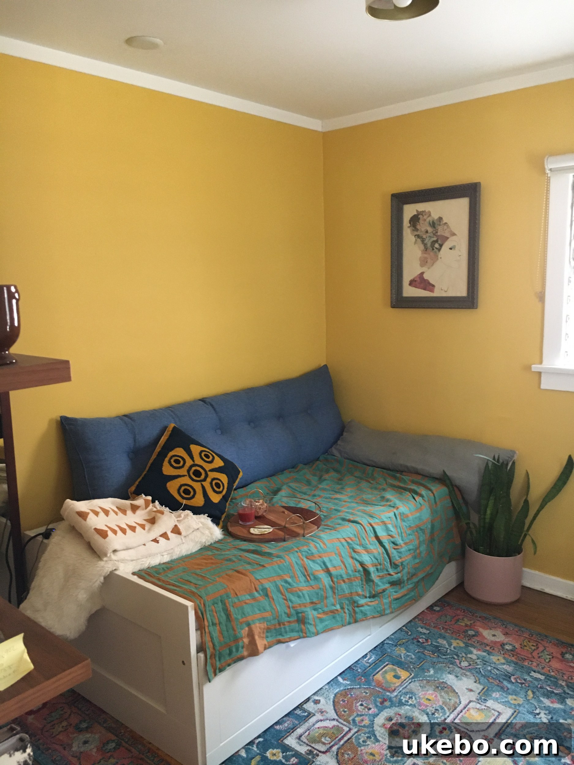 Before image of the small guest room/office with golden yellow walls but dim lighting