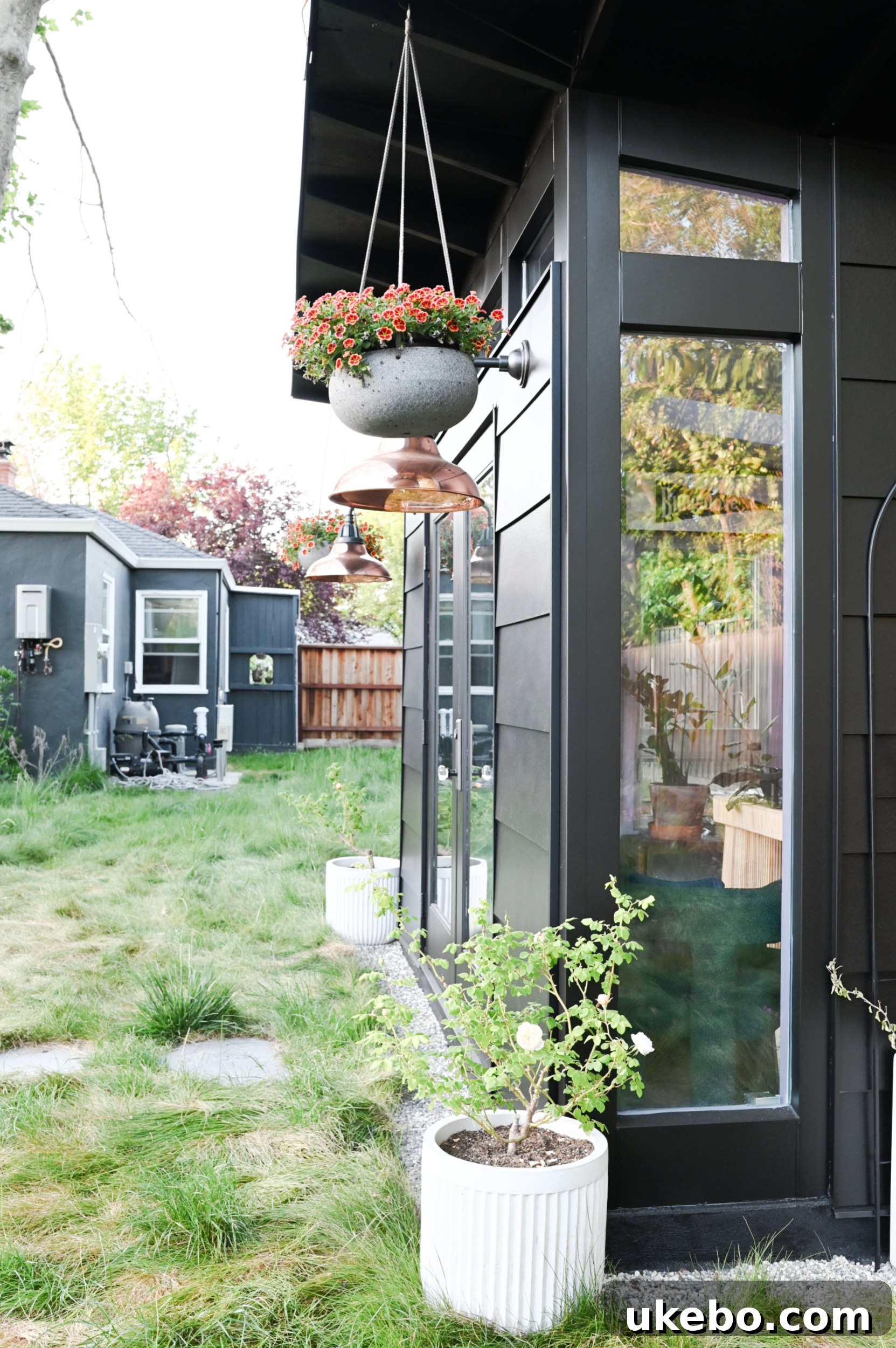 Panoramic view of the completed SG Style Studio integrated into the backyard landscape, surrounded by new plantings.