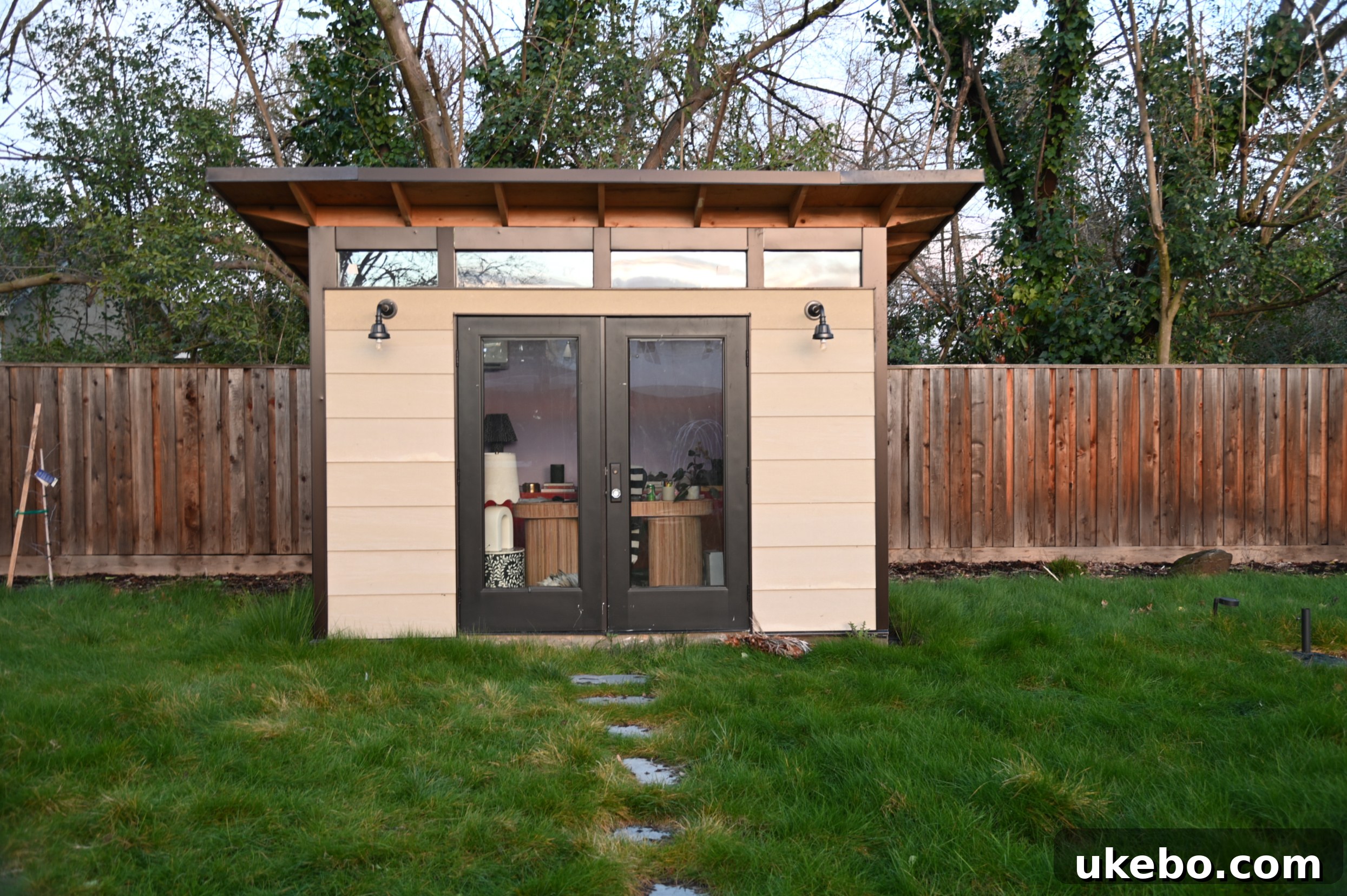 Exterior view of the backyard office studio before painting, showing pre-primed lap siding and raw eaves.