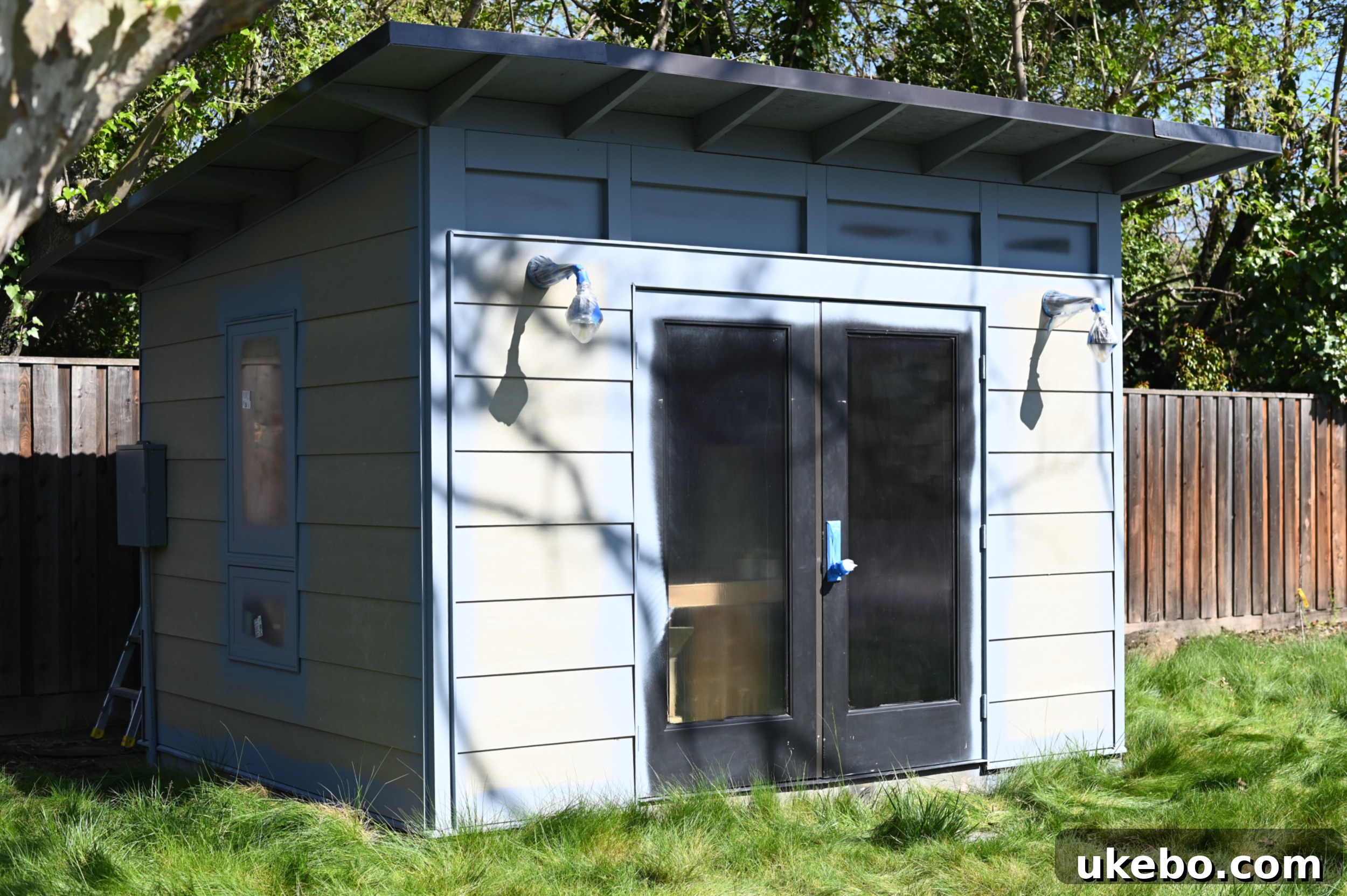 Detail of the studio exterior with windows masked off with liquid, showing the bronze trim before painting.